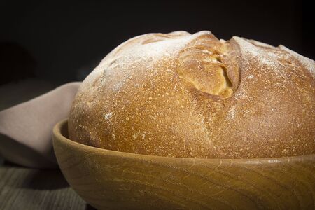 Plate with a loaf of bread on a table of old wood