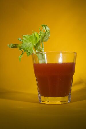 Bloody Mary cocktail with a branch of celery on a yellow backgroundの写真素材