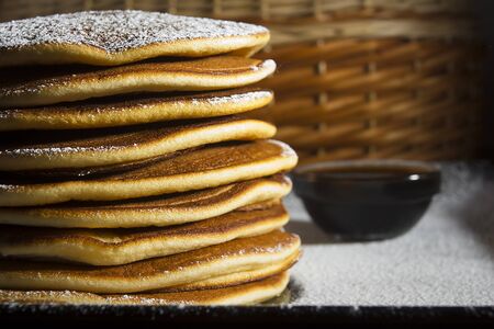 A stack of pancakes on a plate sprinkled with powdered sugar