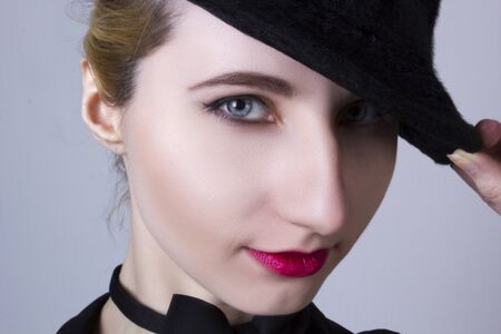 Portrait of a young beautiful woman in studio, holding a hat