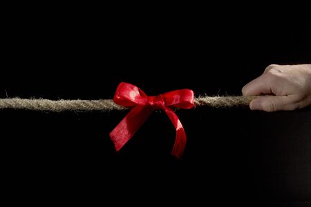 Hands of a man pulling a rope on a black background