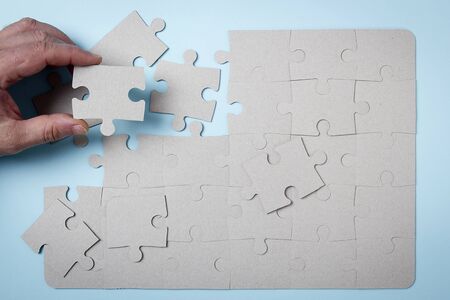 Hand puts puzzle on a blue background