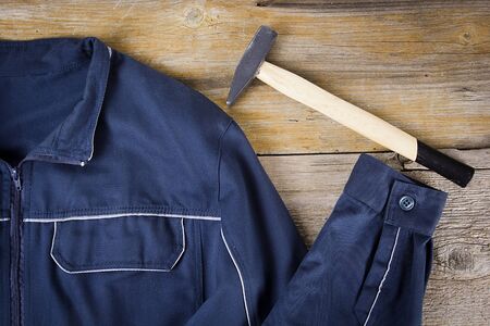 Work clothes and hammer on old wooden background