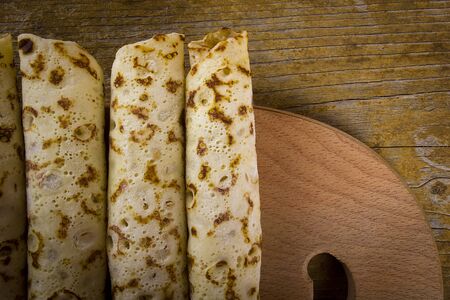 Pancakes with sweet cream on a wooden board