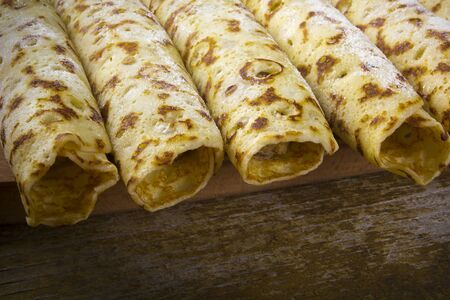 Pancakes with sweet cream on a wooden board