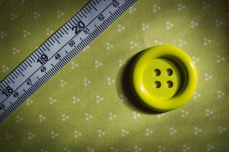 Button and tailor meter on green cloth