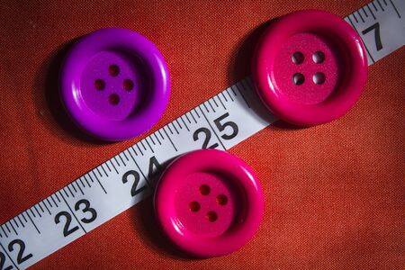 Buttons and tailor meter on fabric background