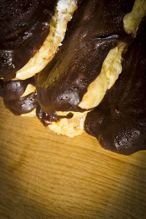 Eclairs with chocolate icing on a wooden table