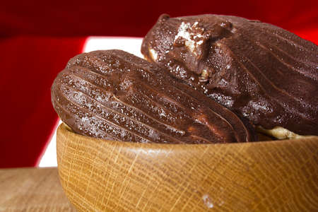 Eclairs with chocolate icing on a wooden table