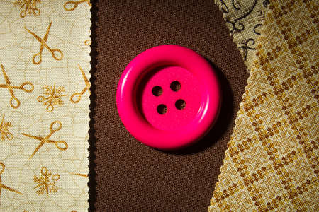Button and fragments of fabric on a wooden table