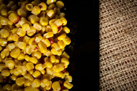 Tinned corn with pepper on a black plateの写真素材