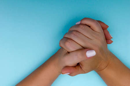 Folded female hands on a blue backgroundの写真素材