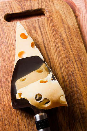 Cheese and cheese knife on wooden cutting board