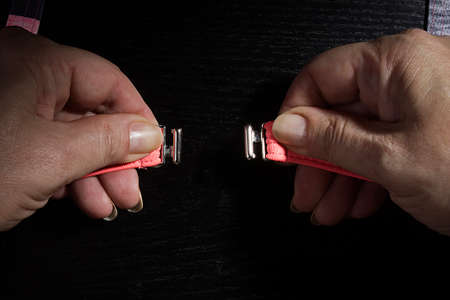 Female hands buttoning a swimsuit on a black backgroundの写真素材