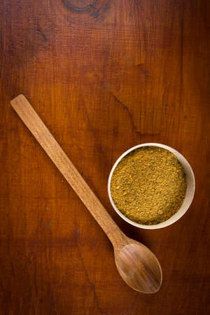 Yellow spice in a wooden bowl with a wooden spoon on the tableの写真素材