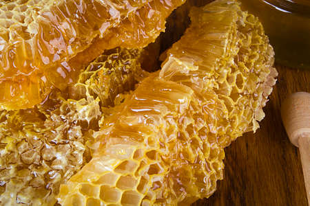 Yellow Honey and Honeycomb slice on a wooden table