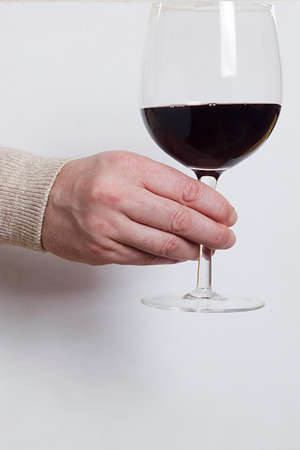 Male hand with glass of red wine on white backgroundの写真素材