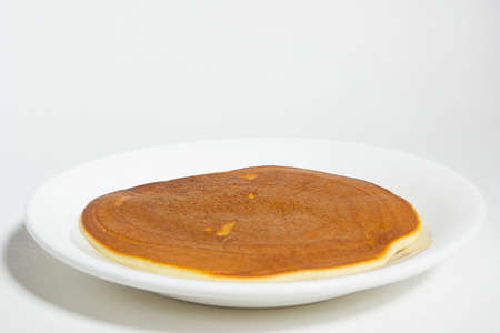 Freshly baked pancake on a plate on a white background