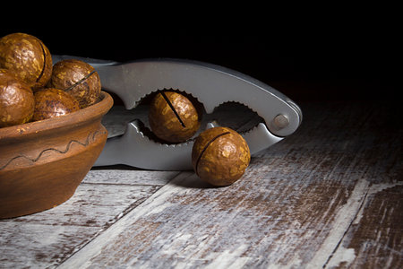 Macadamia nuts and nutcracker on wooden table