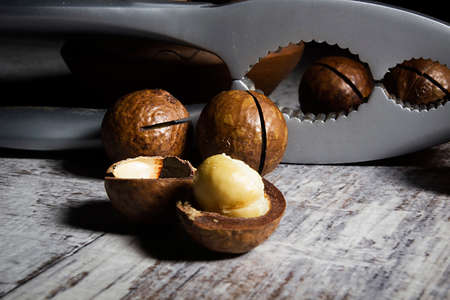 Macadamia nuts and nutcracker on wooden table