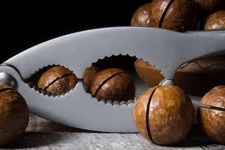 Macadamia nuts and nutcracker on wooden table