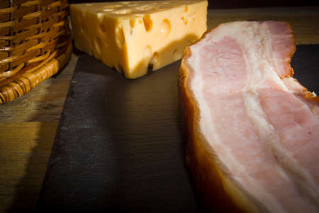Cheese and bacon on a cutting stone boardの写真素材