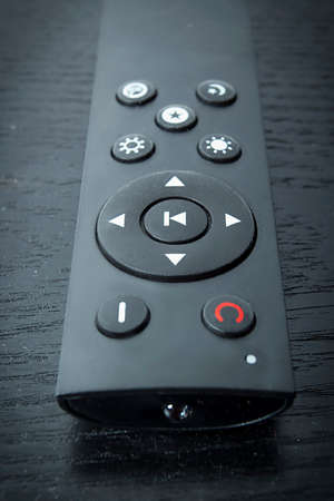 Black remote control on wooden table close up