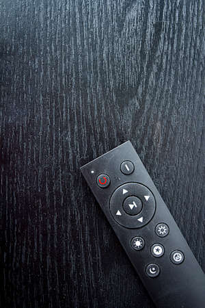 Black remote control on wooden table close up