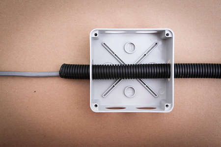 White electrical junction box with wires on beige background