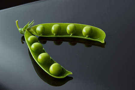 Fresh raw green peas in a pod on a black backgroundの写真素材