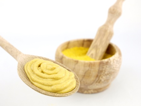Mustard powder in a wooden mortar and mustard on spoon の写真素材