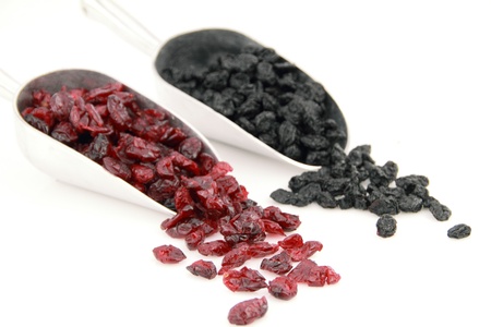 Dried cranberries and blueberries in scoop over white background の写真素材