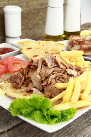 Plate of traditional Greek gyros or Turkish kebab with meat, fried potatoes, tomato and onionの写真素材