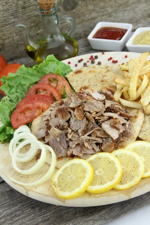 Plate of traditional Greek gyros or Turkish kebab with meat, fried potatoes, tomato and onionの写真素材