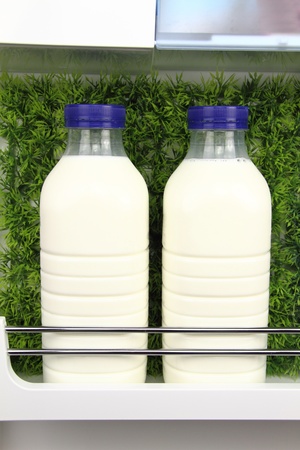 Bottles of fresh milk in the fridge with grass backgroundの写真素材