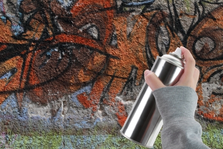 Human hand holding a graffiti Spray can in front of a colorful wallの写真素材