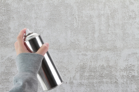 Human hand holding a graffiti Spray can in front of blank concrete wallの写真素材