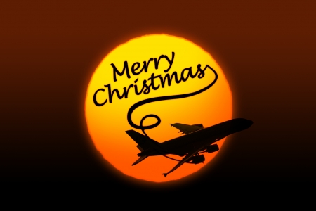 Sunset background with silhouette of airplane and greeting Christmas textの写真素材