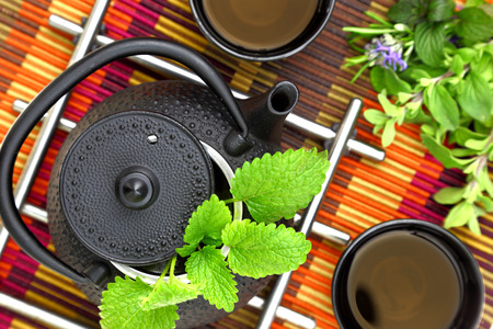 Tabletop with oriental teapot and cup with fresh herbsの写真素材
