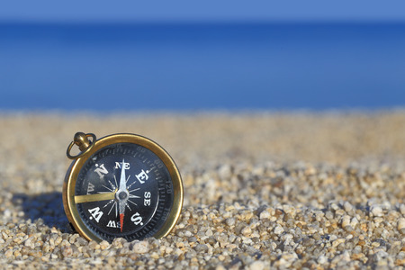 Old compass on the beach with sand and sea の写真素材