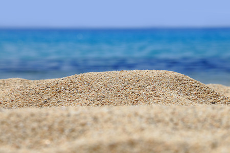 Sandy beach closeup with blur blue sea behind の写真素材