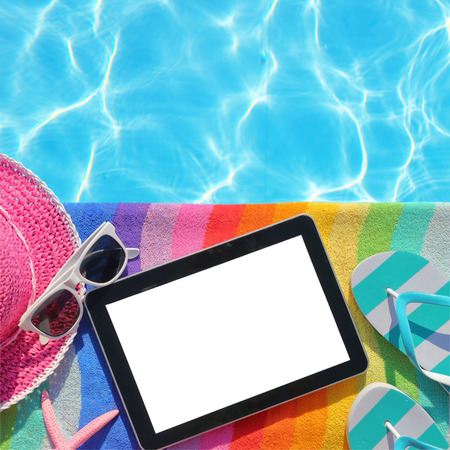 Tablet with blank screen by poolside with beach accessories の写真素材