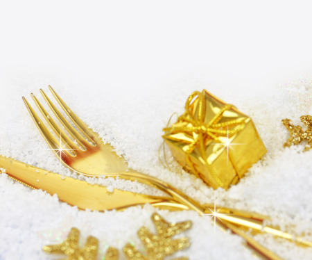 Christmas golden cutlery and ornaments on snowの写真素材