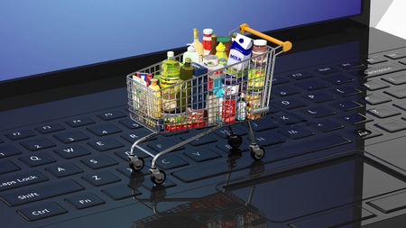 Full with products supermarket shopping cart on black laptops keyboardの写真素材