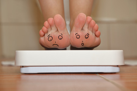 Feet on bathroom scale with hand drawn sad cute facesの写真素材