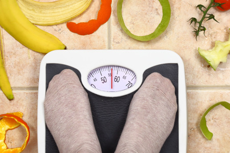 Feet on bathroom scale with fruit peals aroundの写真素材