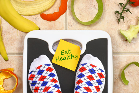 Feet on bathroom scale with Eat Healthy text fruit peals aroundの写真素材