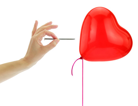 Nail about to pop a heart balloon isolated on whiteの写真素材