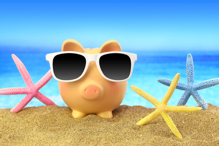 Summer piggy bank with sunglasses and starfishes on beachの写真素材