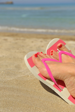 Womans feet with flip flops on the sandの写真素材